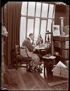 Will R. Barnes in een gewaad, zittend aan zijn bureau in zijn studio, 1903